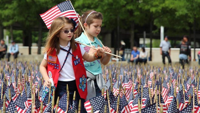 Volunteers place flags for veterans for Memorial Day Vigil