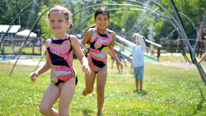 Arabella Murphy, left, and Ha Long Tran run through sprinklers at Creative Themes Day Camp in Perinton. The two, who are both five years old and Pittsford residents, are part of several hundred kids who come to the camp throughout the summer.