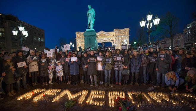 People stand in front of the word Kemerovo, made up of candles, to commemorate the victims of Sunday's fire in a shopping mall in the Siberian city of Kemerovo, in Pushkin Square, with a Pushkin monument in the background, in Moscow, on Tuesday, March 27, 2018.