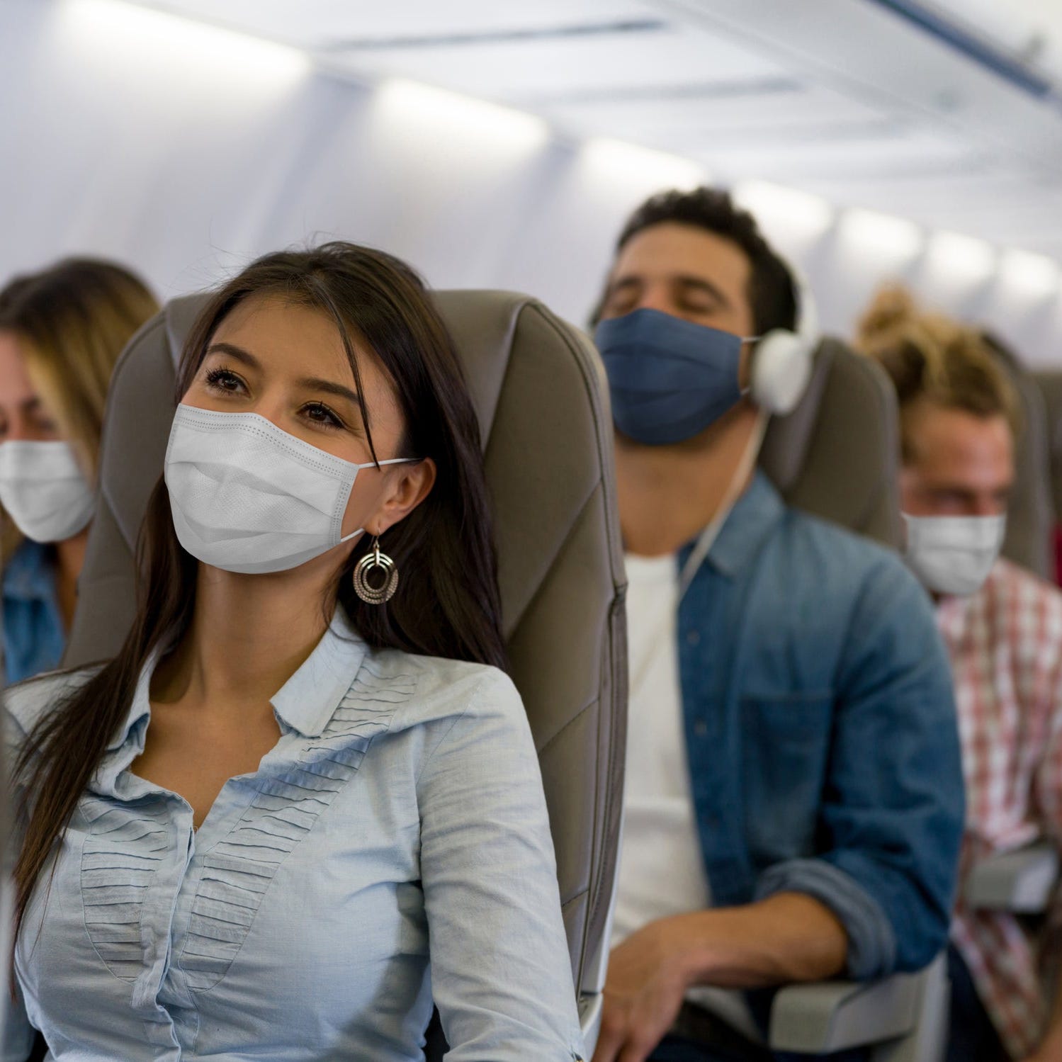 A woman wears a face mask while traveling on an airline during the COVID-19 pandemic.