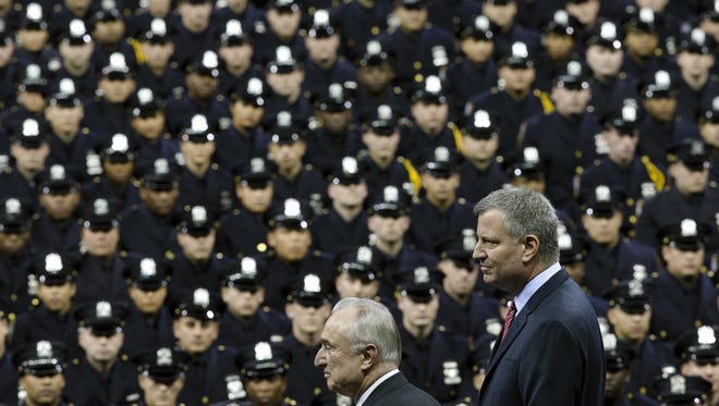 New York City Mayor Bill de Blasio, right, and NYPD police commissioner Bill Bratton, center, stand on stage during a New York Police Academy graduation ceremony, Monday, Dec. 29, 2014, at Madison Square Garden in New York. Nearly 1000 officers were sworn in as tensions between city hall and the NYPD continued following the Dec. 20 shooting deaths of officers Rafael Ramos and Wenjian Liu.