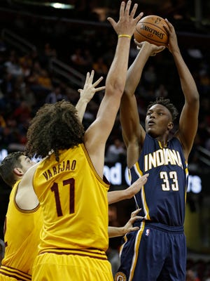Indiana Pacers' Myles Turner, right, shoots over Cleveland Cavaliers' Joe Harris, left, and Anderson Varejao in the second half of an NBA preseason basketball game, Thursday, Oct. 15, 2015, in Cleveland. The Pacers won 107-85. (AP Photo/Tony Dejak)