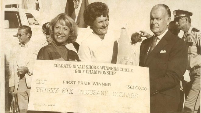 Dinah Shore (left) and Colgate Palmolive President David Foster present a check for $36,000 to 1977 tournament winner Kathy Whitworth.