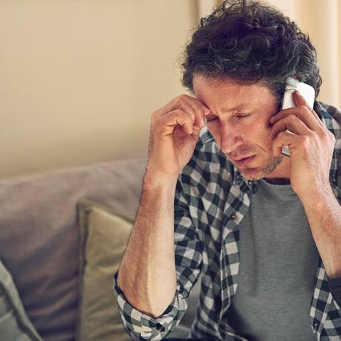 A man looking worried while on a phone call sittin