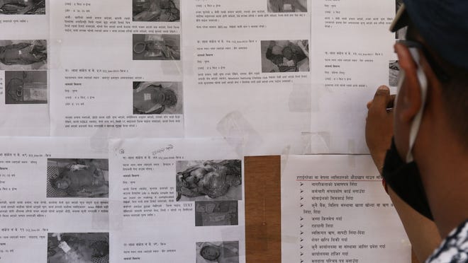 Nepali police superintendent Prakash Adhikari studies descriptions of unidentified bodies outside of Tribhuvan University Teaching Hospital in Kathmandu.