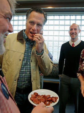 Mitt Romney, second from left, samples reindeer sausage offered by Bill McKeever, left, as Romney campaigns for Alaska Republican Senate candidate Dan Sullivan, on Nov. 3, 2014, at the City Diner in Anchorage Alaska.