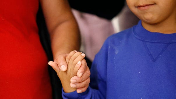 Darwin Micheal Mejia, right, holds hands with his mother,