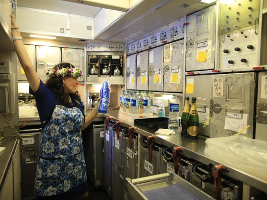 A crew member prepares beverages in the rear galley