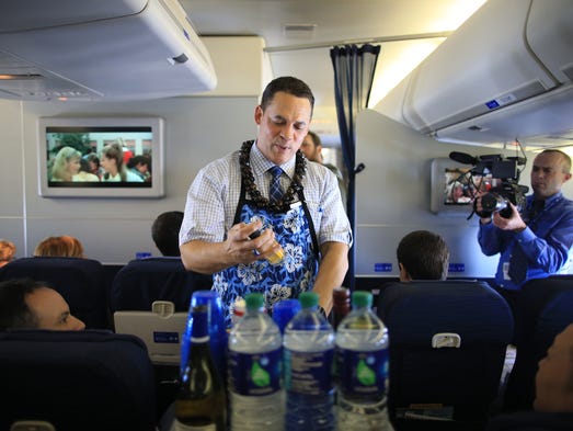 Crew members serve drinks to passengers aboard the