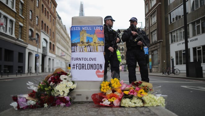 Armed police stand guard in front of floral tributes on Southwark Street near the scene of last night's terrorist attack on June 4, 2017 in London, England. Police continue to cordon off an area after responding to terrorist attacks on London Bridge and Borough Market where 7 people were killed and at least 48 injured last night. Three attackers were shot dead by armed police.