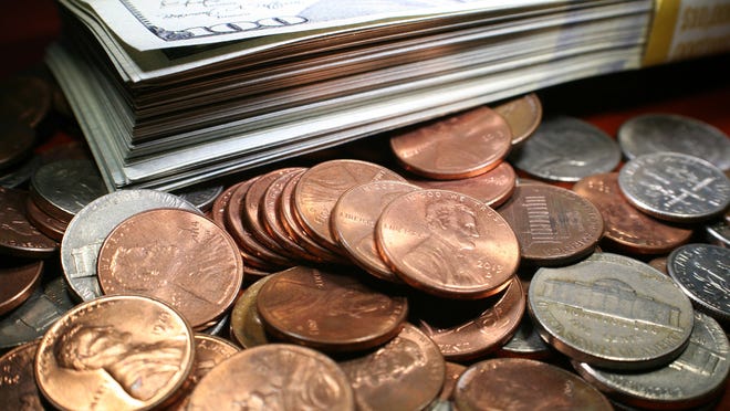 A stack of $100 bills on a cluster of coins