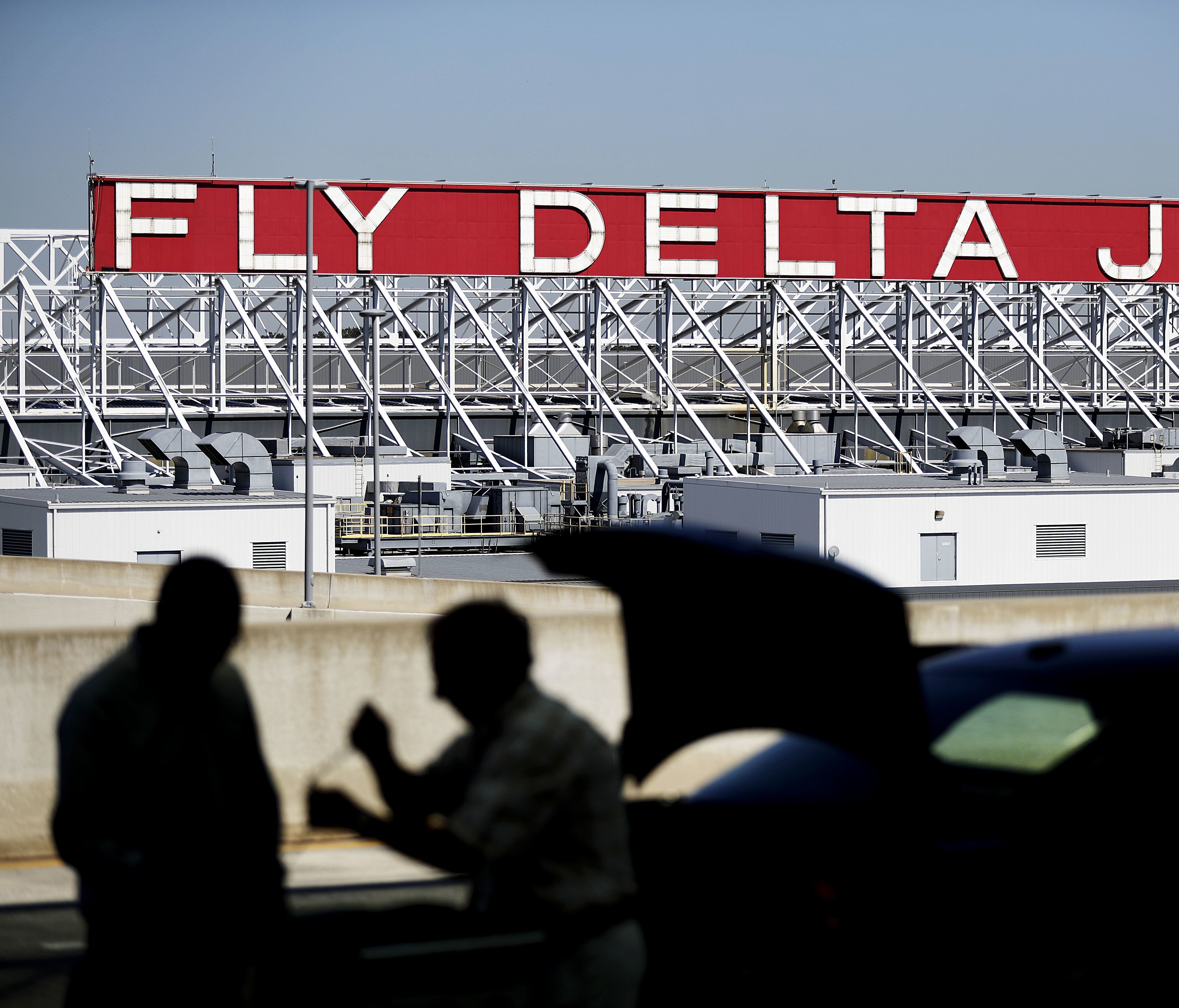 In this Thursday, Oct. 13, 2016, file photo, a Delta Air Lines sign overlooks the unloading area at Hartsfield-Jackson Atlanta International Airport,