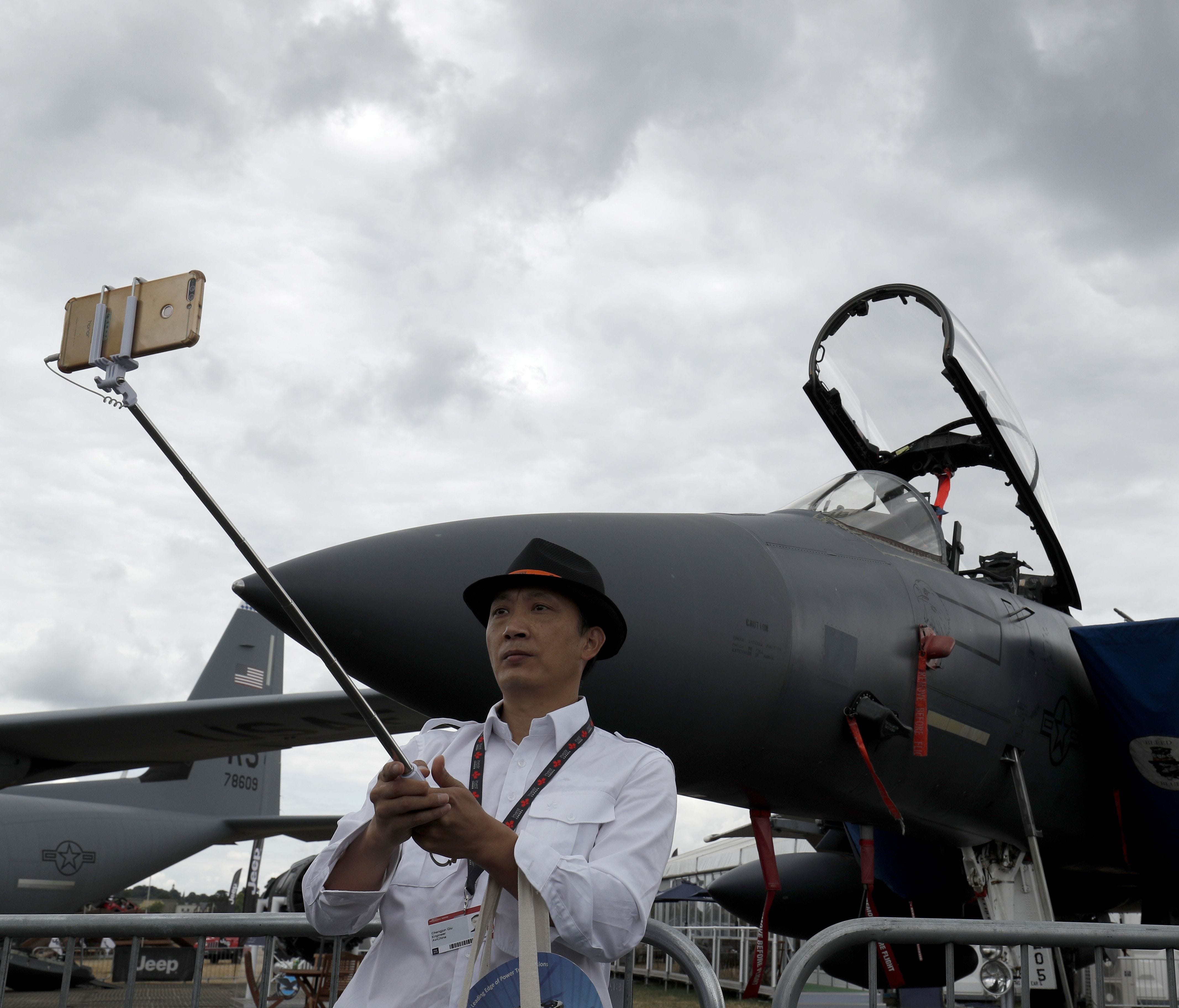A visitor takes a selfie photograph in front of a Boeing F15E MultiRoll fighter aircraft displayed at the Farnborough Airshow on July 18, 2018.