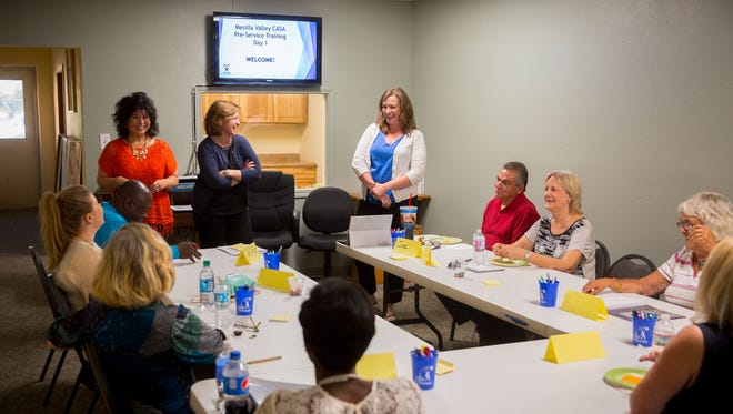 Mesilla Valley CASA staff and volunteers gather at the CASA offices for the beginning of 30 hours of training in April 2016. Doreen Gallegos is at the head of the table in a red shirt. Brandie White is in white cardigan at head of table. Training sessions are now done by videoconferencing.