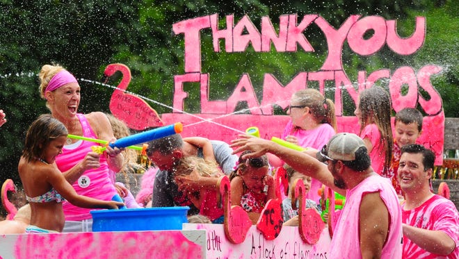 The parade turns into a water fight during the annual Pink Flamingo Slo-Pitch Tournament and Festival in De Pere, Saturday, July 12, 2014.