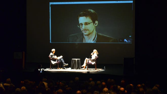 Whistle-blower Edward Snowden appears via video link Monday during a lecture at the Englert Theatre. On stage are activists Ray McGovern and Coleen Rowley.