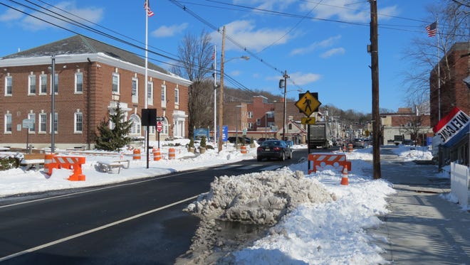 Orange barriers mark the position of new sidewalk bump-outs for snowplow drivers unfamiliar with Millburn's new Complete Streets construction.