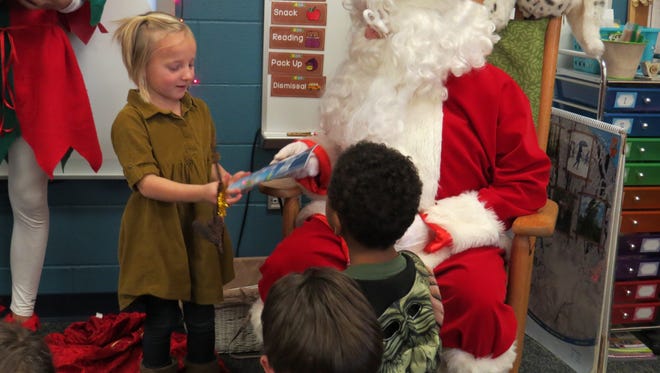 Sierra Zanoni receives a book from Santa at Bataan Memorial Primary. "Reading with Santa" was part of a project organized by the PCHS National Honor Society.