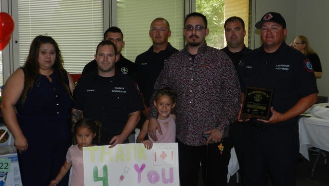 Sergio Flores, and members of the Flores family pose with the local paramedics who were the first responders on the scene of an accident on U.S. Highway 62/180 in which Flores was injured. 
Flores’s daughters presented the paramedics with a poster that read “Thank you for saving Daddy” during an awards ceremony hosted by the Carlsbad Medical Center May 17.
