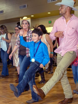 Zane Silva, of Team Zane, kicks up his heels with Amanda Poole, L, and Siddeeq Shabazz, R, at Saturday nights 7th Annual Team Zane Celebrity Waiter and Jardin de Los Niños Urban Cowboy Charity Event held at the Las Cruces Convention Center.