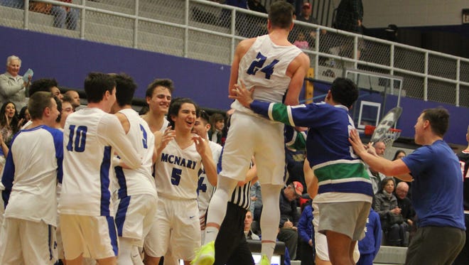 McNary's Ricardo Gardelli (24) is mobbed by a fan while his teammates celebrate after a win against McMinnville on Wednesday, Feb. 21, 2018.