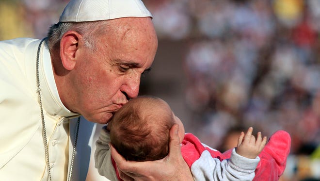 Pope Francis kisses a baby as he arrives at the Artemio Franchi stadium to celebrate a mass during his visit to Florence, Italy, Tuesday, Nov. 10, 2015.