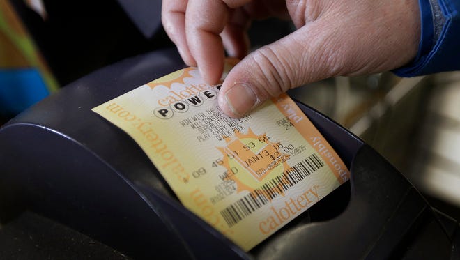 In this Jan. 13, 2016, file photo, a store clerk removes a Powerball quick pick lottery ticket in Oakland. The Powerball drawing for Wednesday, Feb. 22, 2017, soared to $403 million after no one matched all six numbers for the drawing Saturday, Feb. 18, 2017.