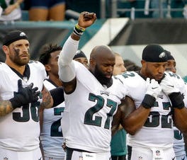 Chris Long (56) puts his left arm around Malcolm Jenkins as Jenkins raises his fist during the national anthem Thursday night.