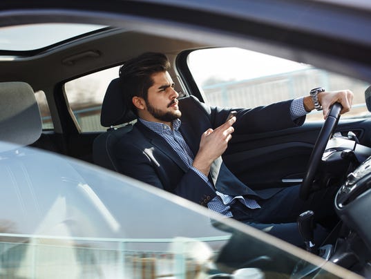 Handsome businessman texting message on the phone in car.