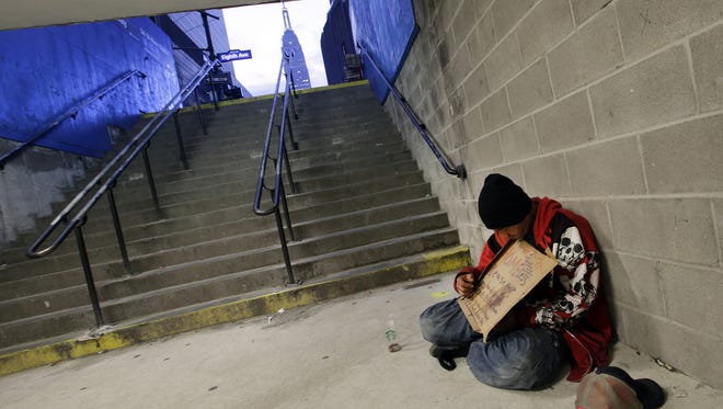 A homeless man holds a sign asking for money in October while sitting at the entrance to a subway station in New York. Gov. Andrew Cuomo  has issued an executive order requires that homeless people are taken to shelters when the temperature drops below freezing.