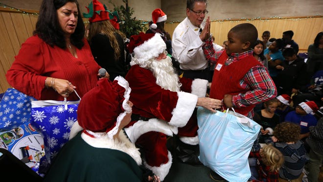 Marilyn and Daniel Schievella of Leonia as Santa and Mrs. Claus with their son Undersheriff for the Morris County Sheriff's Office William Schievella getting a high-five from Khyree after getting his gift bag during the Italian American Police Society of New Jersey's annual Big Brothers and Sisters of New Jersey Children's Christmas Party at the Whippany American Legion Hall. December 19, 2015, Whippany, NJ.