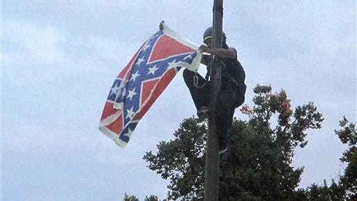Bree Newsome of Charlotte, N.C., removes the Confederate battle flag at a Confederate monument at the Statehouse in Columbia, S.C., on Saturday, June, 27, 2015. She was taken into custody when she came down. The flag was raised again by capitol workers about 45 minutes later.  (AP Photo/Bruce Smith)