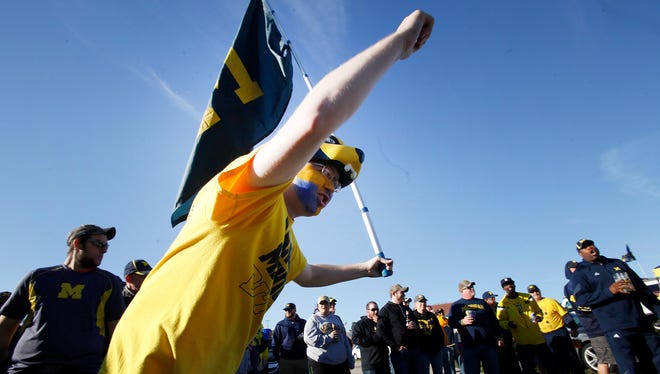 A fan runs and waves the Michigan flag as he tailgates with friends before the start of the Michigan-Oregon State game on Sept. 12, 2015 in Ann Arbor.