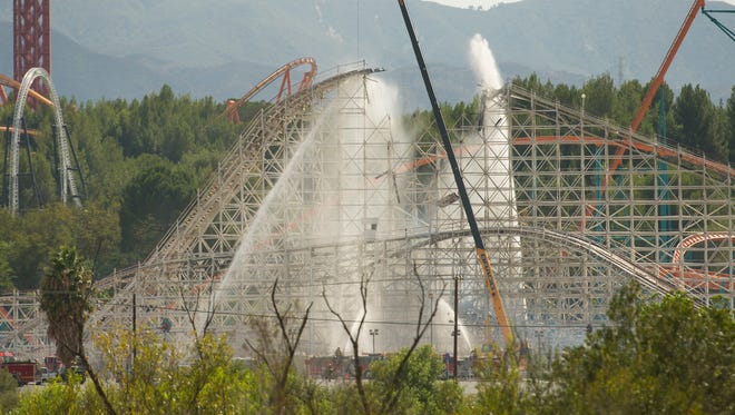 Crews pour water on the Colossus wooden roller coaster at Six Flags Magic Mountain after a fire broke out on the top of the amusement ride. The Colossus was shutdown recently after the park announced it would modernize the classic wooden roller coaster.