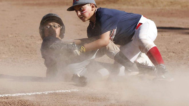 El Paso Sun Warriors player Matthew Anakin Torres, 9, slid into third base while Darian Diaz, 10, from the Las Cruces Rebels, looked up for the umpire's call during a USSSA World Series game on July 4 in Las Cruces. The Rebels won the game 11-5. The boys' fathers – Paul Torres and Javier Diaz – played on the same team when they were 12, and always talked about their boys sharing the same field one day. This was the day.