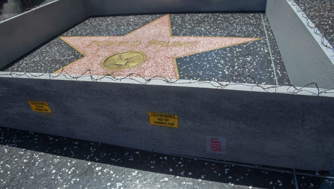 Tiny razor wire and a sign that reads "Keep Out" in Spanish and English surrounds Donald Trump's star on the Hollywood Walk of Fame Tuesday, July 19, 2016.