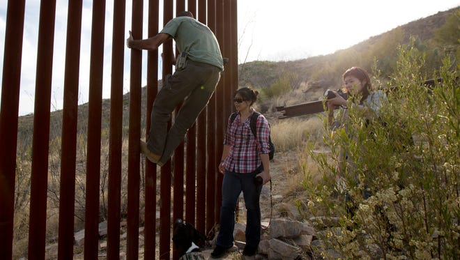 Tim Foley shows how to climb a section of the border wall separating Mexico and the United States near where it ends as journalists Chitose Nakagawa, right, and Marcie Mieko Kagawa look on in Sasabe, Ariz.