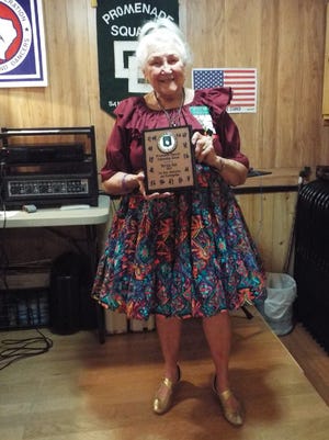 Patricia Cain, on the stage of Promenade Square, displays the plaque indicating she is the recipient of the Square Dance Fellowship Award. She received it on April 5 for her involvement in and the support of the square dance community in San Angelo. Her participation has spanned 36 years.