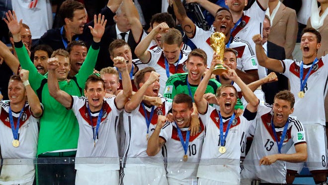 Germany's team captain Philipp Lahm lifts the trophy surrounded by his teammates after the World Cup final soccer match between Germany and Argentina at the Maracana Stadium in Rio de Janeiro, Brazil, Sunday, July 13, 2014. Germany beat Argentina 1-0 to win the World Cup.