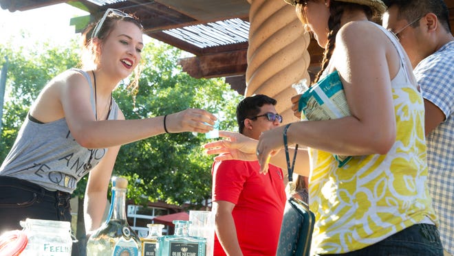 Meghan Lang, left, serves up Blue Nectar tequila to Alicia Grijalva, and Jonathan Annua on Saturday, July 21, 2018, during the fourth annual Tequila, Taco & Cerveza Festival at the Plaza de Las Cruces.