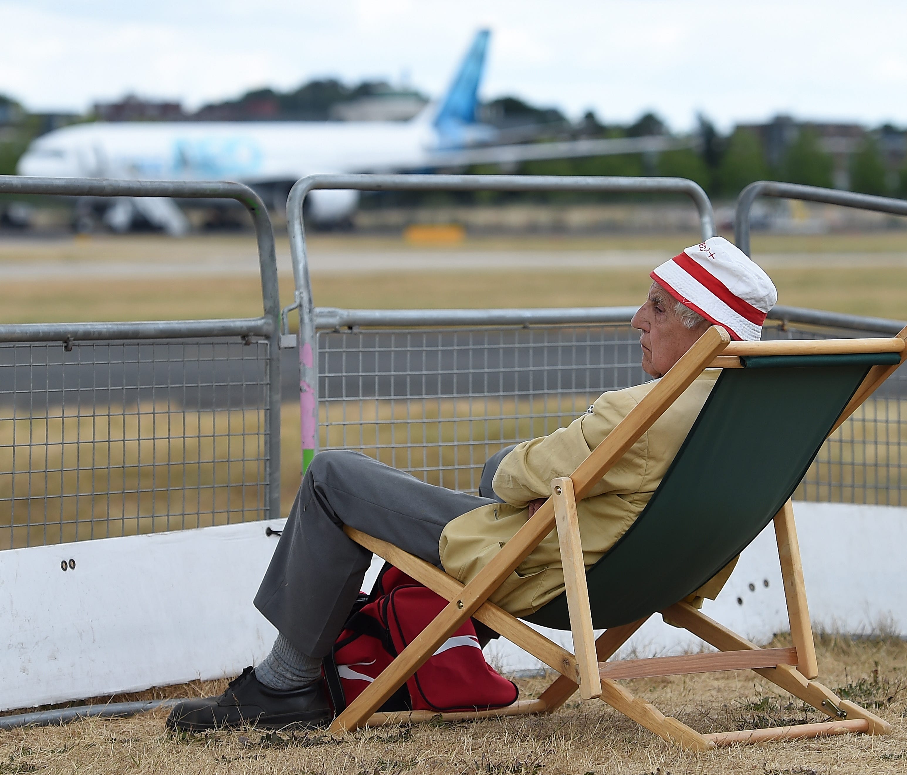 An aircraft enthusiast has a deck chair set up to watch the flight shows of various planes at the Farnborough International Airshow on July 17, 2018.