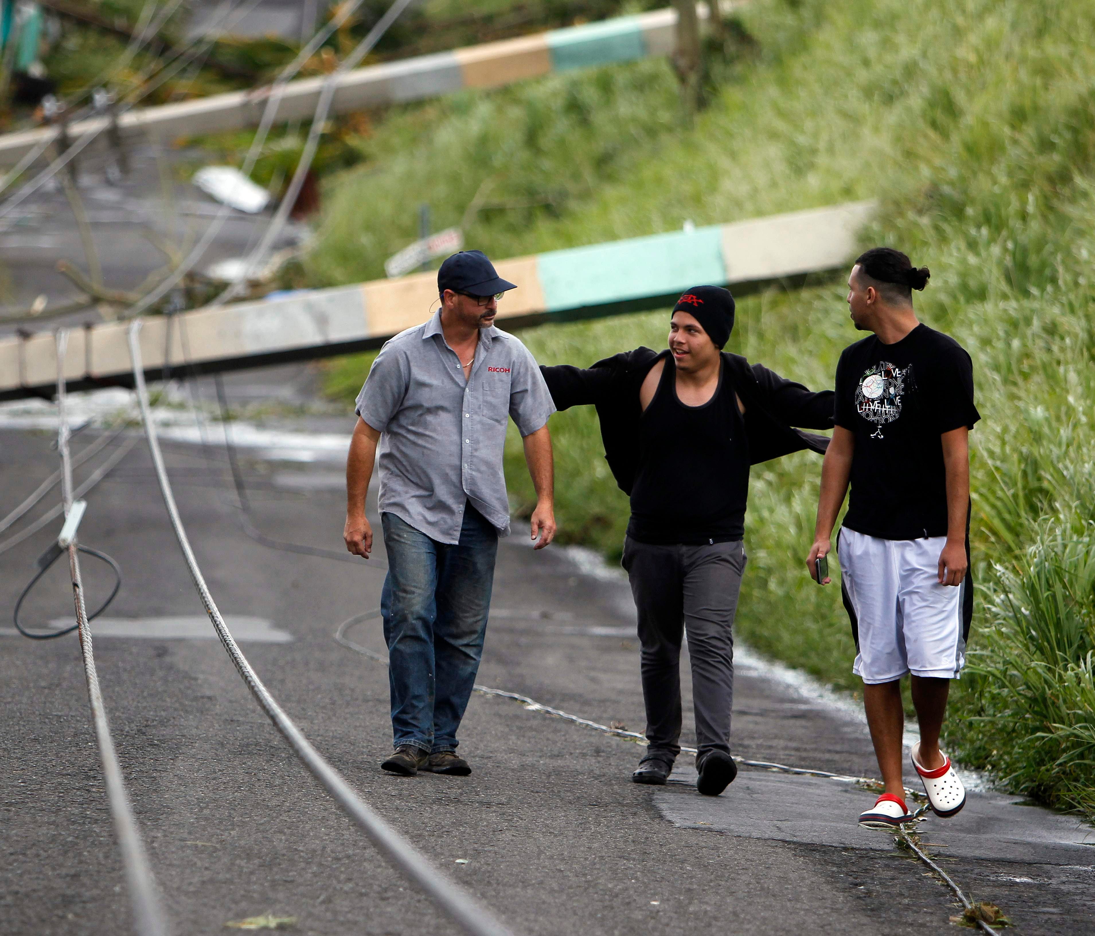 Three men walk between downed power lines in the aftermath of Hurricane Maria in Luquillo, Puerto Rico on Sept. 21, 2017.  