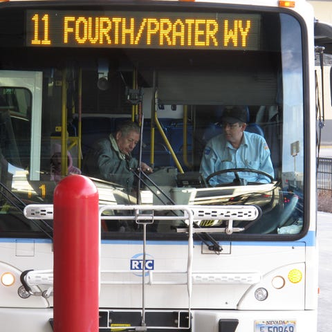 A passenger boards a city bus while the driver loo
