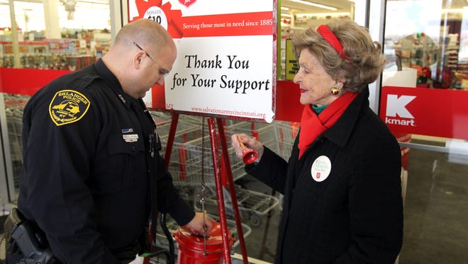 In this 2010 photo, Mary Middleton (right) rings a bell at a Salvation Army red kettle in Erlanger as Erlanger Police Officer Darryl Jouett makes a donation.
