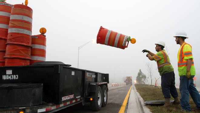 Road crew workers with Prince Construction remove traffic barricades along the newly opened airport direct connect road to I-75 Friday morning.