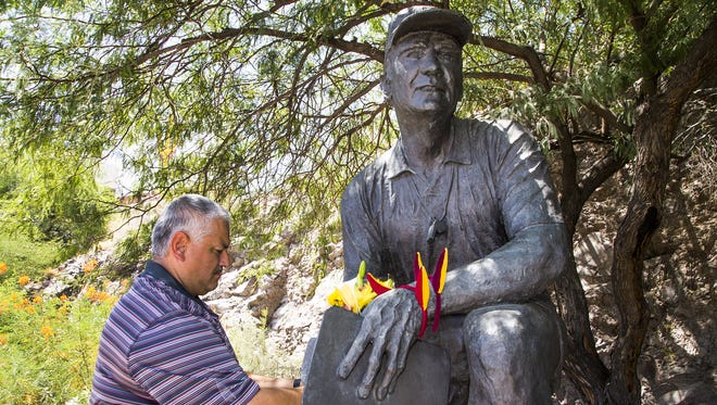 Raul Monreal, 45, Chandler, brings flowers to the statue of Arizona State University Head Coach Frank Kush outside Sun Devil Stadium, Thursday, June 22, 2017.
