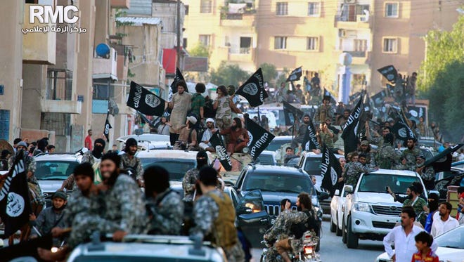 In this undated file image posted on June 30, 2014, by the Raqqa Media Center of the Islamic State group, a Syrian opposition group, which has been verified and is consistent with other AP reporting, fighters from the Islamic State group parade in Raqqa, northern Syria.