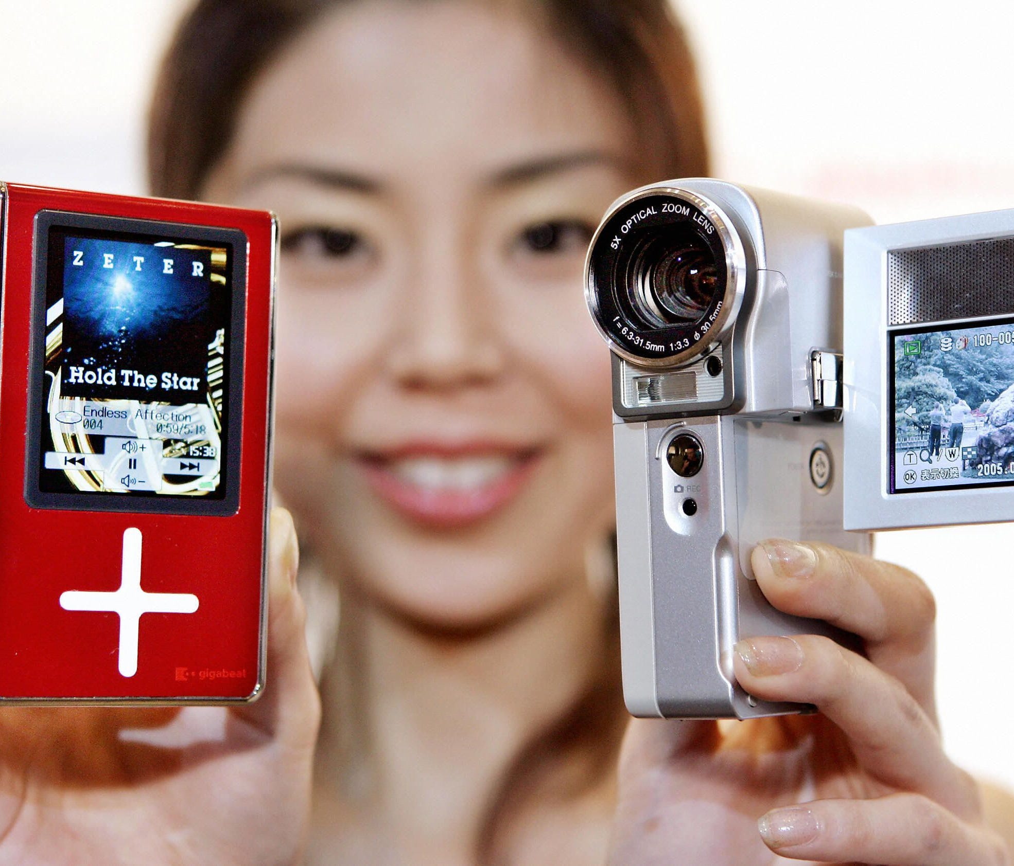 In this 2005 photo, a woman holds Toshiba's  hard disk camcorder Gigashot V10 and a hard disk audio player Gigabeat X30.