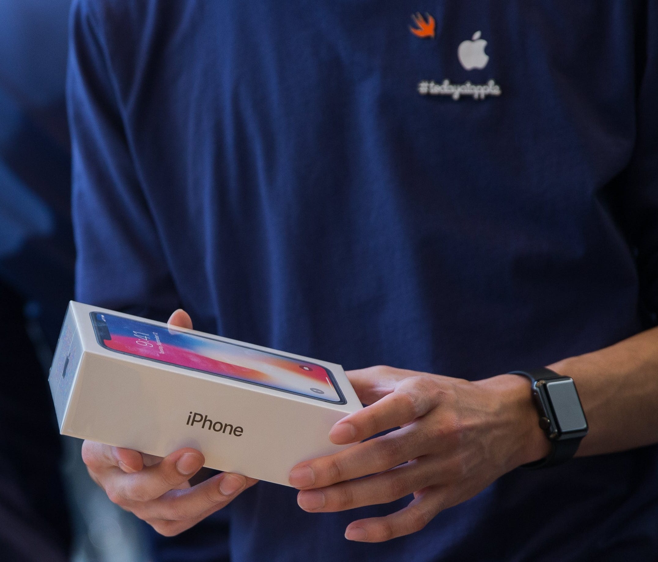 A Apple employee holds the new iPhone X inside the Apple Store in the Omotesando shopping district in Tokyo, Japan.