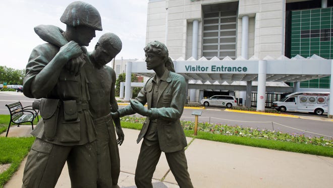 FILE ART - Three statues portraying a wounded soldier being helped, stand on the grounds of the Minneapolis VA Hospital, Monday, June 9, 2014. An audit of 731 VA hospitals and clinics found that a 14-day goal for seeing first-time patients was unattainable given increasing demand for health care. The VA said Monday it was abandoning the scheduling goal. (AP Photo/Jim Mone)